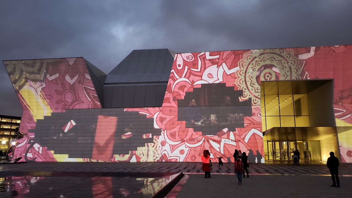 The Museum's facade covered in a red mandala pattern with cut-outs featuring performances.